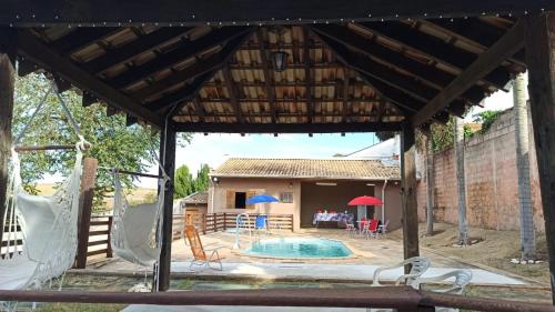 a pavilion with a pool and a house at Chácara Refúgio da Carol in Taubaté