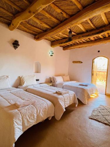 Aït YousにあるRiad Ecobioの木製の天井の部屋にベッドが2つある