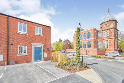 un edificio de ladrillo con una puerta azul en un aparcamiento en Contractors & Families Delight - Spacious 3-Bed Accommodation Sleeps 7, Snooker Table, Smart TV, Netflix, Parking, Derby City Centre en Derby