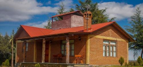 ein Haus mit Kamin und rotem Dach in der Unterkunft Cabañas El huizache in Huasca de Ocampo