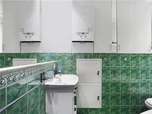 a green and white bathroom with a sink and toilet at Mieszkanie u Ewy 100 m do plaży z ogródkiem in Sopot
