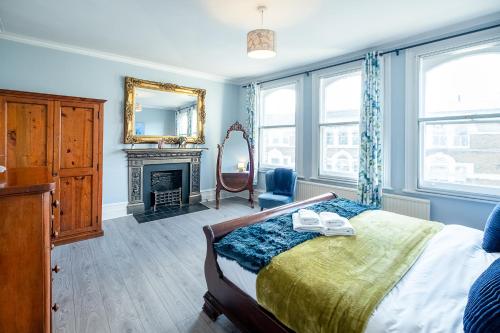 a bedroom with a bed with a mirror and a fireplace at Stylish & Cosy 3bdr In Fulham with roof terrace in London