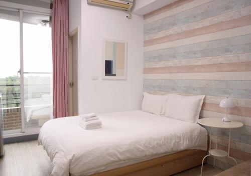 a bedroom with a bed with a striped accent wall at 夕映安平 in Tainan