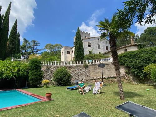 a group of people sitting in a yard in front of a house at La Torre de Vilanna in Bescanó