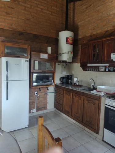 cocina con armarios de madera y nevera blanca en Magia en Sierra de la Ventana