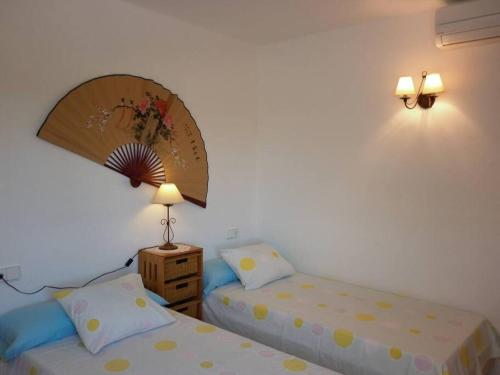 two beds in a room with a mirror and two lamps at beautiful views with pool in ibiza in Sant Miquel de Balansat