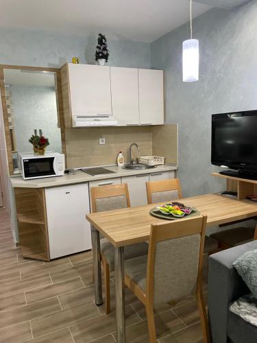 eine Küche mit einem Tisch und eine Küche mit weißen Schränken in der Unterkunft Apartmani Dušica Konaci Kopaonik in Kopaonik