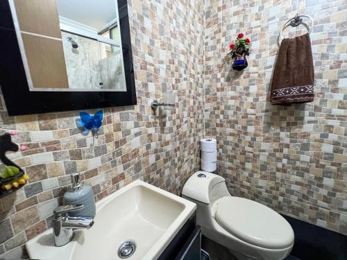 a bathroom with a white toilet and a sink at Elegante apartamento: Sabaneta Central in Sabaneta