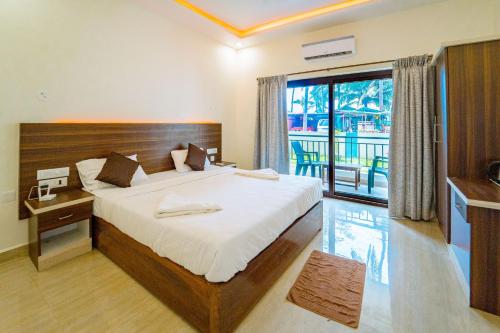 a bedroom with a large bed and a balcony at Darsy Residency in Agonda