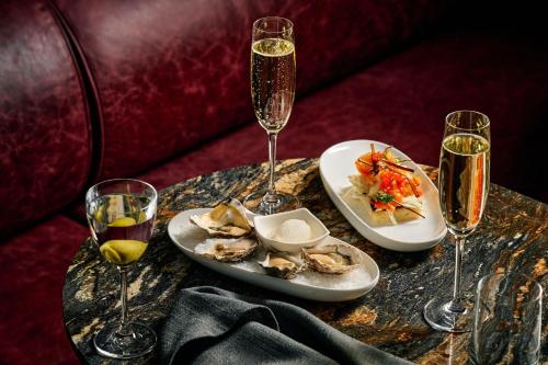 a table with two plates of food and two glasses of champagne at Le Meridien Melbourne in Melbourne