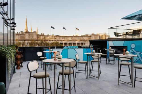 a patio with tables and chairs on a roof at Le Meridien Melbourne in Melbourne