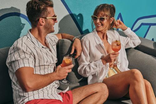 a man and woman sitting on a couch holding drinks at Le Meridien Melbourne in Melbourne