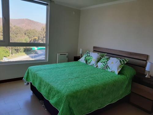 um quarto com uma cama verde e uma grande janela em Dpto 2D1B en Papudo Laguna, Piso 8, Edf Flemenco con vista al mar em Papudo