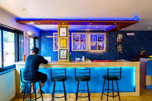 a man sitting at a bar in a restaurant at Darsy Residency and beach cottages in Agonda