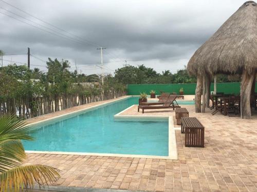 a swimming pool with benches and a grass umbrella at Playa y Luna in Progreso
