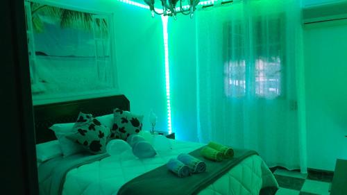 a green room with a bed with flip flops on it at Disfruta de un barrio tranquilo in Alcalá de Guadaira