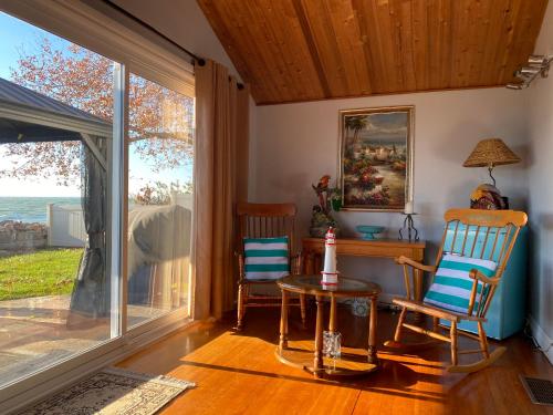 ein Wohnzimmer mit 2 Stühlen, einem Tisch und einem Fenster in der Unterkunft Casa Azul-lakefront in Leamington