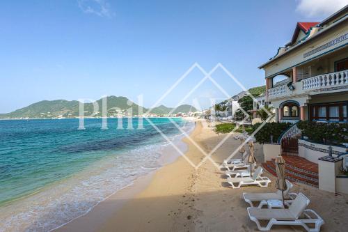 a beach with chairs and a building and the ocean at Magnifique 3 pièces à Gd Case Les pieds dans l'eau in Grand Case