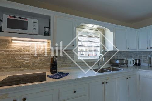 a kitchen with white cabinets and a sink and a microwave at Magnifique 3 pièces à Gd Case Les pieds dans l'eau in Grand Case