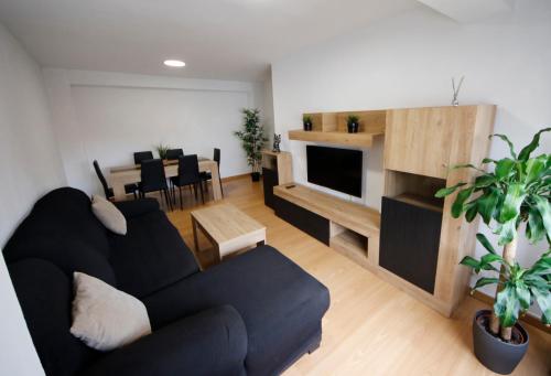 sala de estar con sofá negro y comedor en ACOGEDOR Y LUMiNOSO, en Oviedo