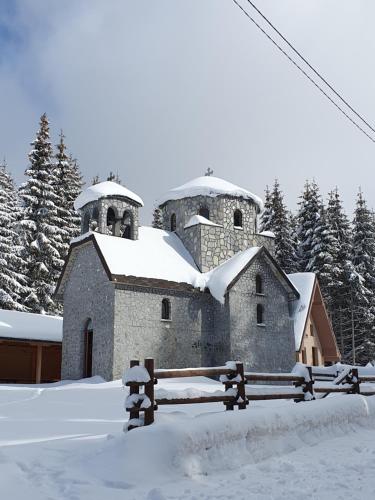 an old stone church with two domes in the snow at Home Belić Golija in Radaljica