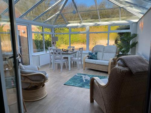 einen Wintergarten mit einem Glasdach mit einem Tisch und Stühlen in der Unterkunft Woodside-Filey in Filey
