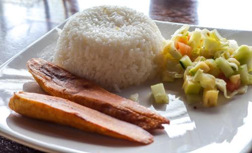 a plate of food with rice and meat and vegetables at Mano Verde Minca in Minca