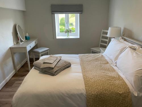 een slaapkamer met een bed, een bureau en een raam bij Winstitchen Cottage in Simonsbath