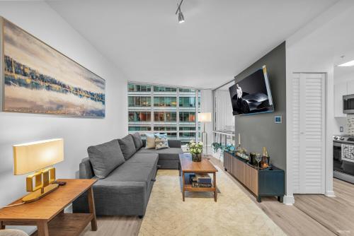 a living room with a couch and a tv at 1-BR Condo in Downtown Coal Harbour with Parking and City Views in Vancouver