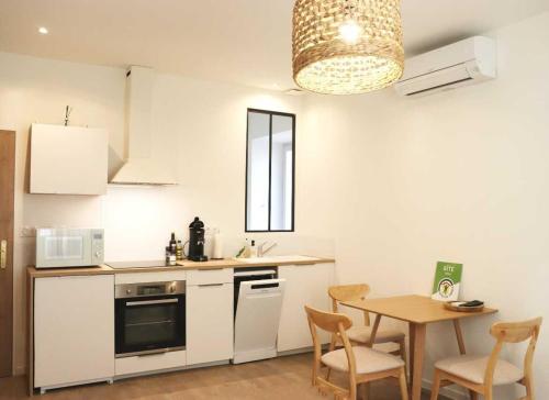 - une cuisine blanche avec une table, une table et des chaises dans l'établissement Charmant studio en plein coeur de Tain l'Hermitage, à Tain-lʼHermitage