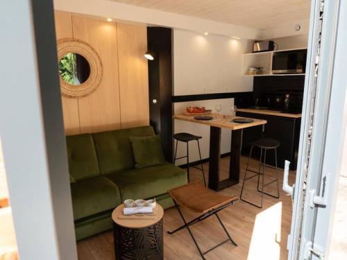 un salon avec un canapé vert et une cuisine dans l'établissement Le repère nature SPA - Lodges de Bonfruit, à Pompierre