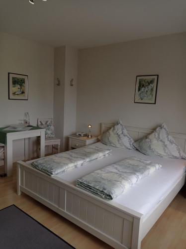 メルスドルフにあるPension Kölzerのテーブル2台付きの客室で、白い大型ベッド1台が備わります。