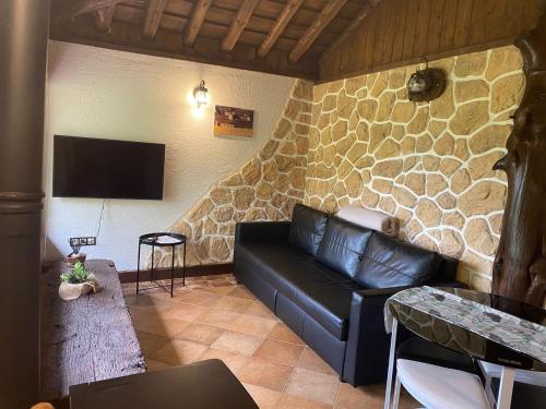 a living room with a leather couch and a stone wall at El BURGO DE OSMA ALOJAMIENTO RURAL VILLA BAGH in El Burgo de Osma