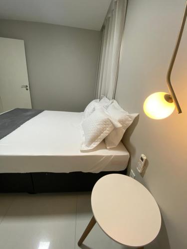 um pequeno quarto com uma cama, uma mesa e um candeeiro em Casa Amora em Arraial do Cabo