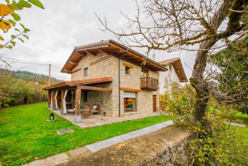 a small stone house with a balcony on a yard at Egur Etxe I Caserío Vasco I Jardín I Porche I BBQ I Chimenea in Zárate
