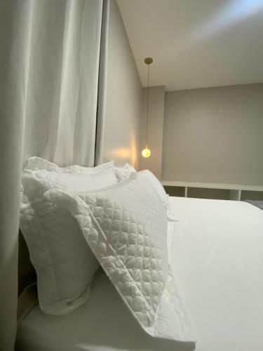 Una cama blanca con un edredón blanco. en Casa Amora en Arraial do Cabo