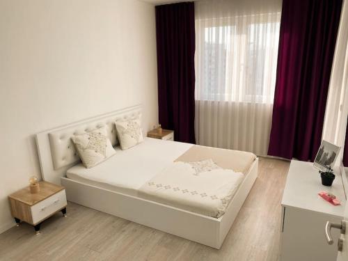 Un dormitorio con una gran cama blanca y una ventana en City Center Apartment, en Ferizaj