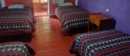 a room with three beds and a wooden floor at Hospedaje La Ñusta in Ollantaytambo