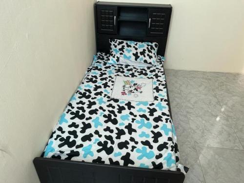 a small bed with a black and blue comforter at Regular homebased room in Sharjah