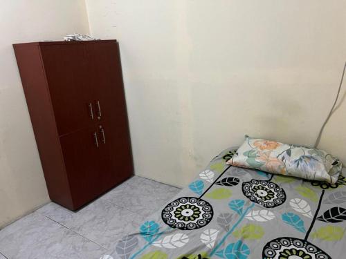 a small bedroom with a bed and a cabinet at Regular homebased room in Sharjah