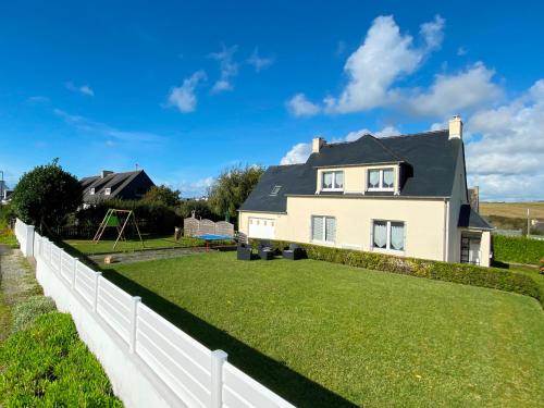 a house with a large yard with a white fence at Maison d'Ys à 500 m de la plage in Saint-Nic