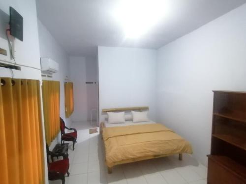 ein kleines Schlafzimmer mit einem Bett und einem Stuhl in der Unterkunft Semar88 Guest House in Balong