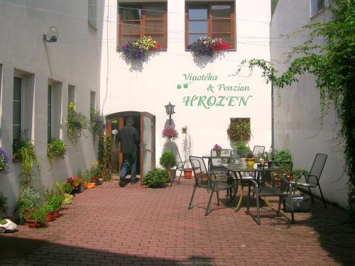 a man walking into a building with tables and chairs at Penzion a Vinoteka Hrozen in Kroměříž