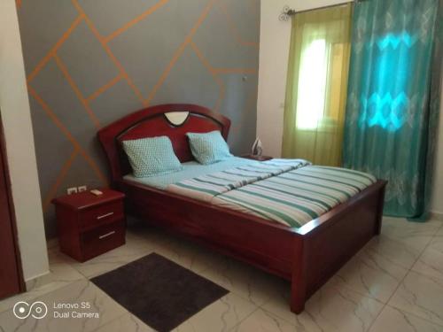 una camera da letto con un letto con testiera in legno e una finestra di Ramakyri room a Douala