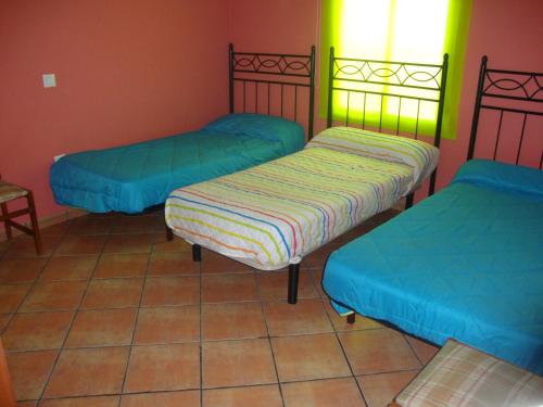 3 camas en una habitación con azul y verde en La Nature alojamiento natural, en La Codosera