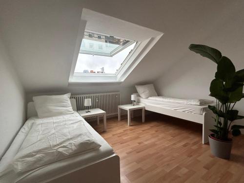una camera mansardata con due letti e una finestra di GardenApartment a Francoforte sul Meno