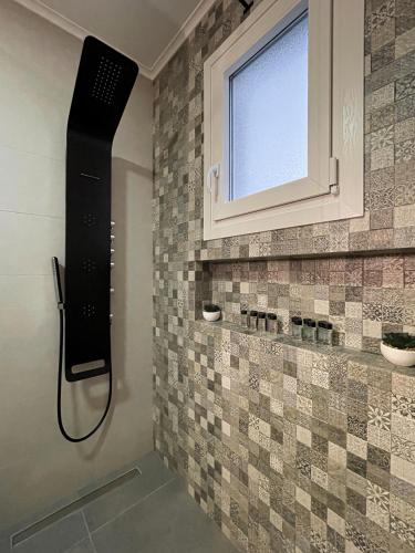 a bathroom with a shower with a window and tiles at Mavromata's Cozy Apartment in Triovasálos