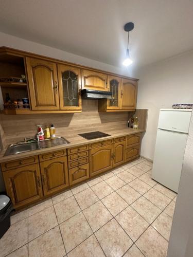 a kitchen with wooden cabinets and a white refrigerator at Chez Sony in Les Mureaux