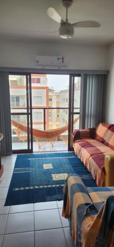 a living room with two beds and a balcony at Apartamento familiar em asturias in Guarujá