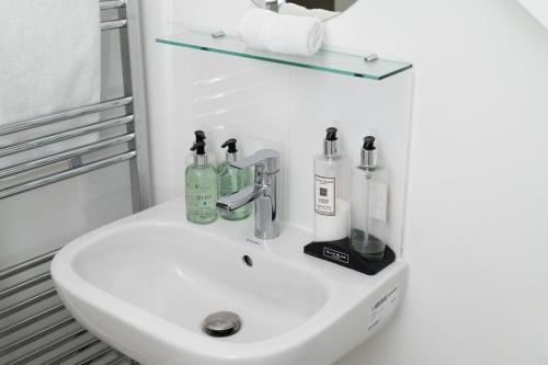 a white bathroom sink with bottles on it at Beautiful cottage style 3-bed By Valore Property Services in Loughton